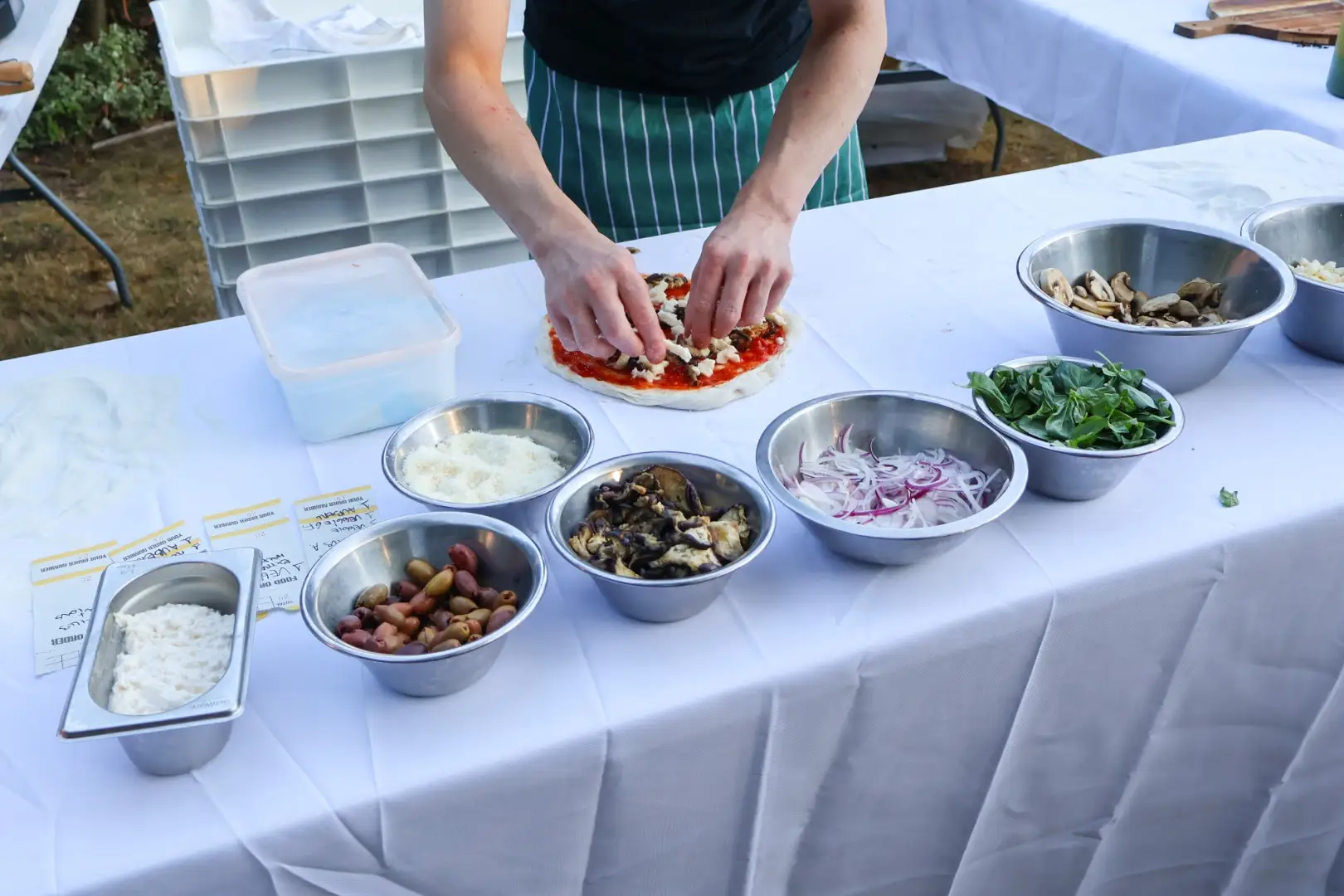 The prep line laid out for a garden party, toppings in steel bowls along a dressed table